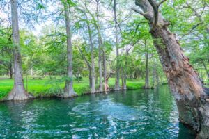 Kate Storm swinging from a metal ring above the water at the Wimberley Blue Hole