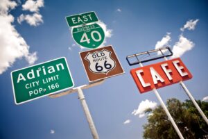 Road signs along Texas Route 66 with Midpoint Cafe sign in the background