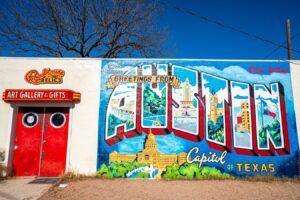 greetings from austin mural on a sunny day with red roadside relics doors to the left