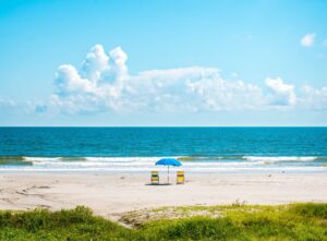 two beach chairs with umbrella on a galveston beach, one of the best beaches near houston texas