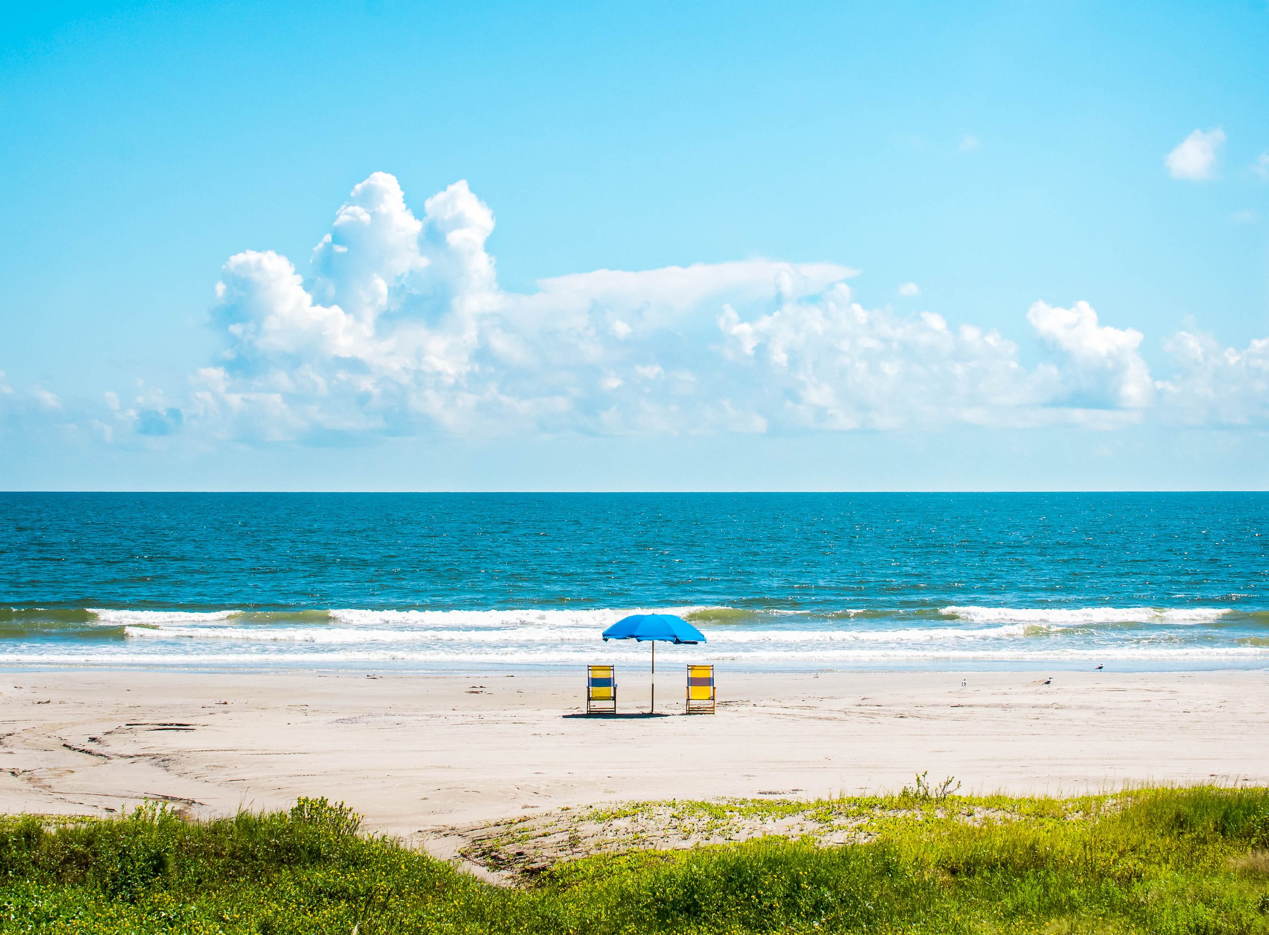 two beach chairs with umbrella on a galveston beach, one of the best beaches near houston texas