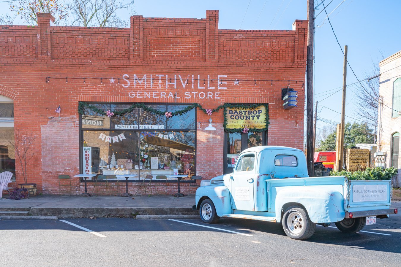 red brick general store with blue historic truck parked out front in smithville tx