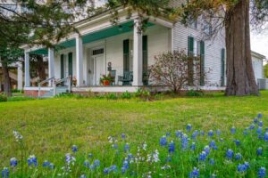 bluebonnets blooming in fron of a house in huntsville, one of the best east texas towns to visit